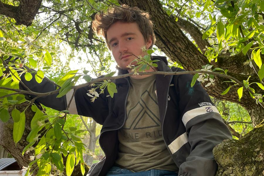 A casual headshot of Tyler Watson, a web developer with a warm and friendly smile, sitting in front of a forest background